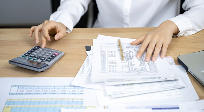 Photo: Person reviewing spreadsheet with pen and calculator